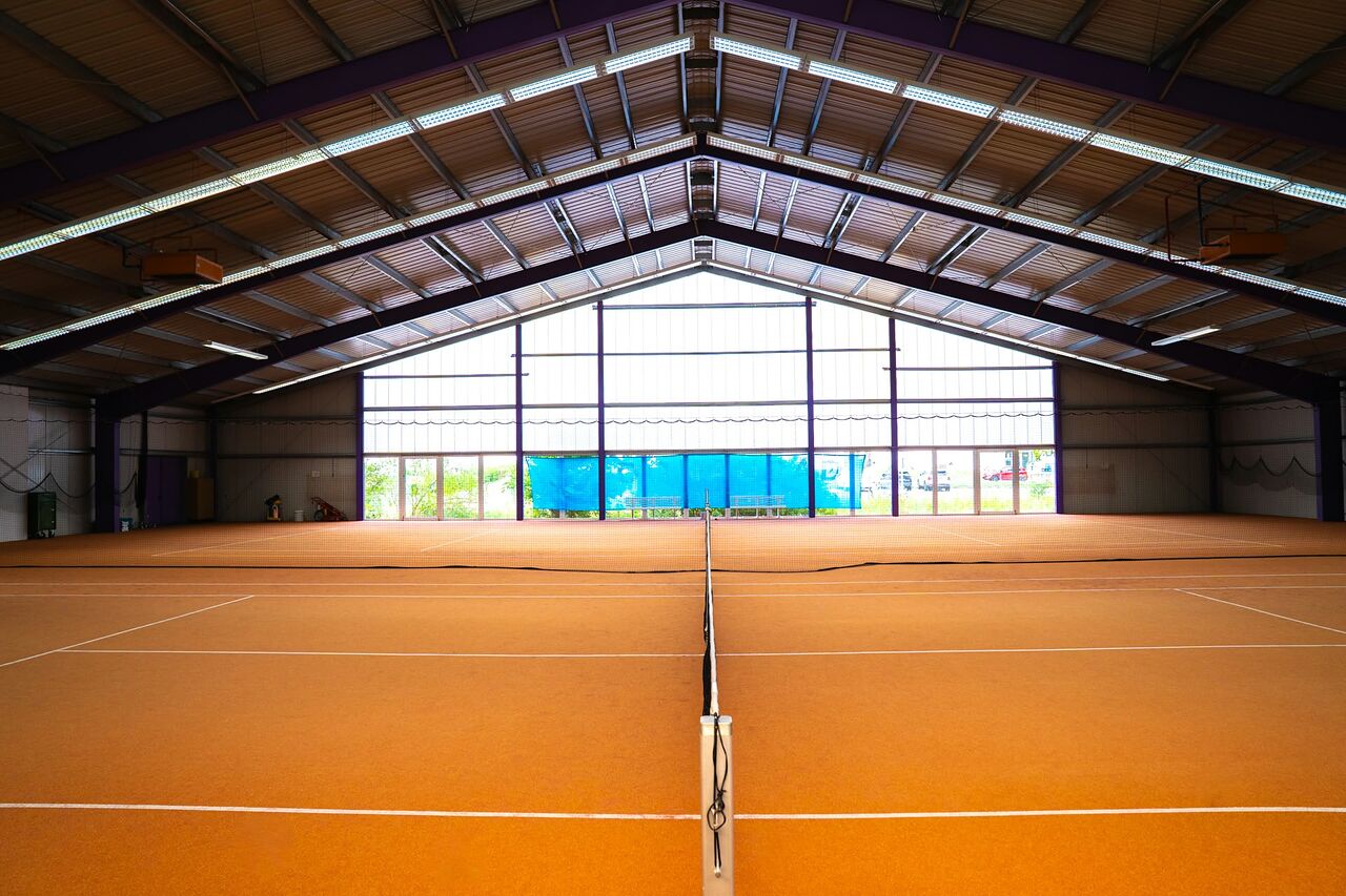 Blick entlang des Netzes durch die Tennishalle des Post-SV Ulm zur Fensterfront